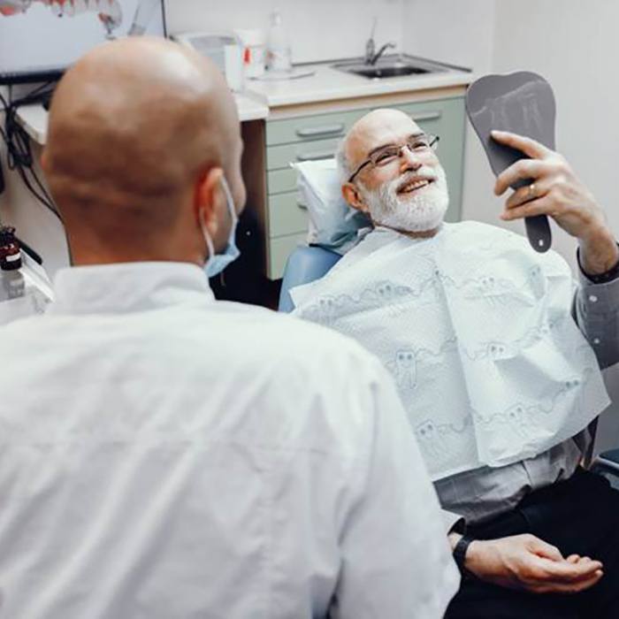 dental patient seeing his new smile after getting dentures