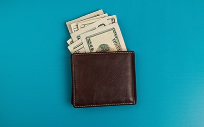Wallet with money sticking out on blue background
