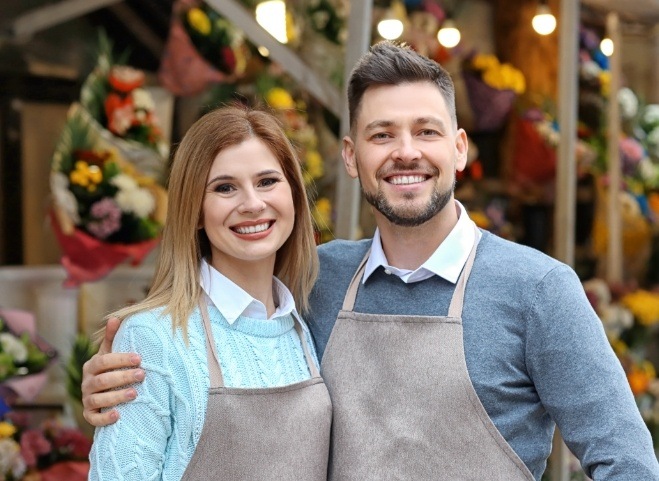 Smiling man and woman wearing aprons and sweaters