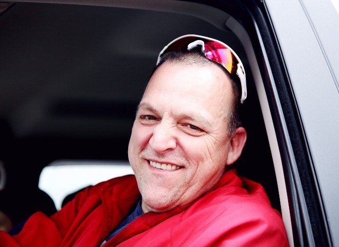 Man smiling with a red jacket and sunglasses
