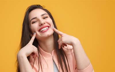 woman smiling and pointing to her smile showing the subtlety of Invisalign