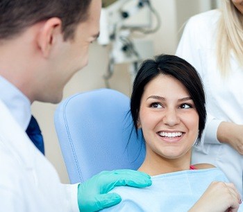 Younger woman in dental chair smiling after dental treatment visit
