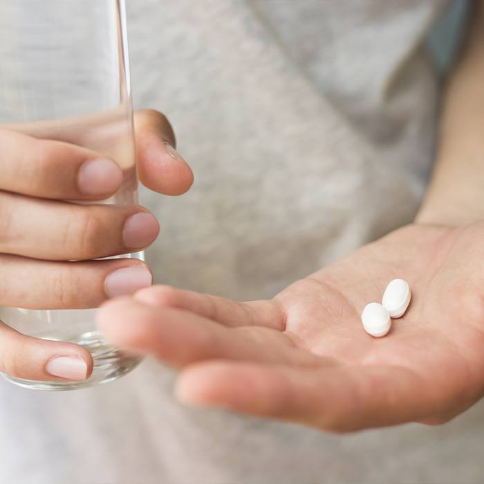 Person holding oral conscious dental sedation pills and glass of water